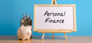 a piggie bank in front of the a jar of pennies at the side of a white board with the words written personal finance