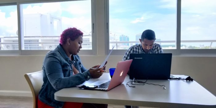 two colleague sitting on a desk doing work on their laptops